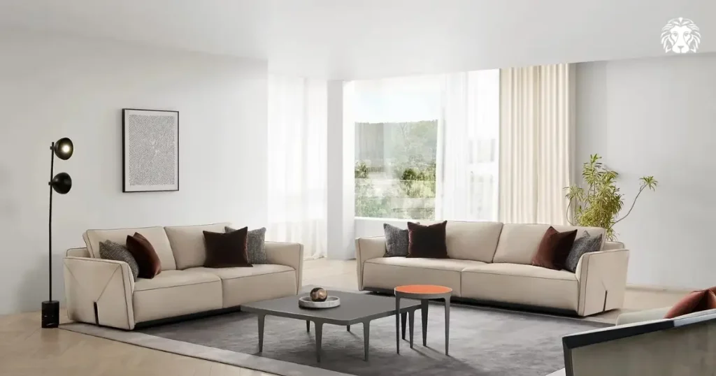 Sofa da lộn ENVELOPE màu kem thanh thoát với chân kim loại cao, điểm xuyết gối tựa đỏ rượu vang tạo chiều sâu quyến rũ